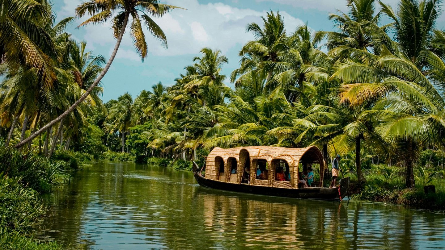 Traditional boat moving through palm-lined Kerala backwaters